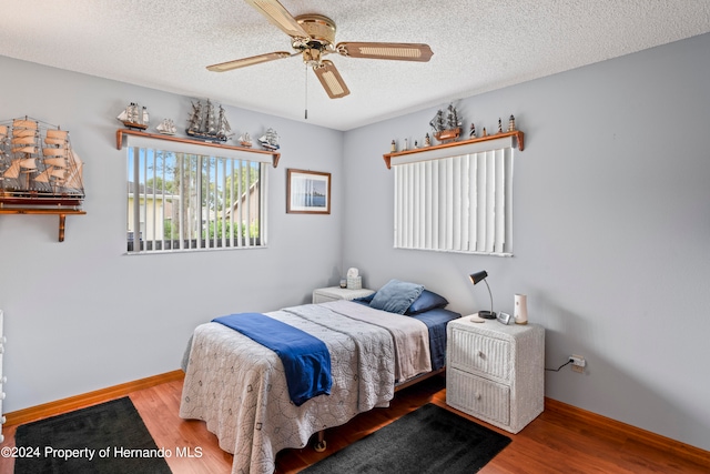 bedroom featuring light hardwood / wood-style floors, ceiling fan, and a textured ceiling