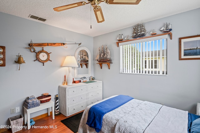 bedroom featuring ceiling fan, a textured ceiling, and wood-type flooring