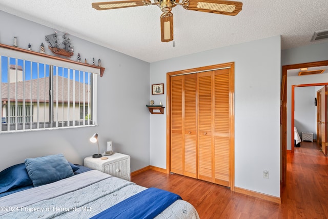 bedroom with a closet, hardwood / wood-style floors, ceiling fan, and a textured ceiling