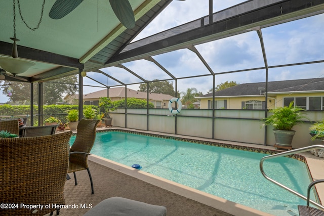 view of pool with glass enclosure, ceiling fan, and a patio area