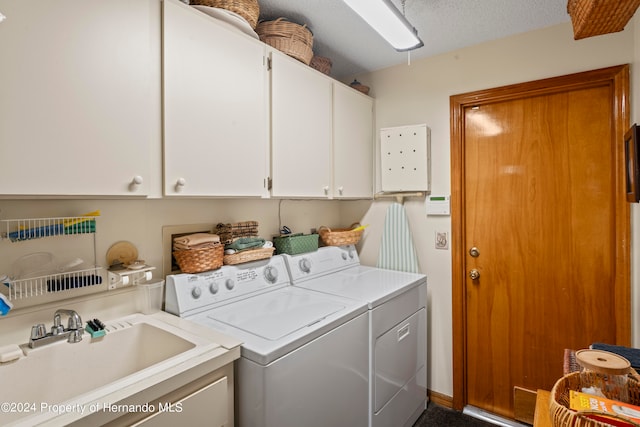 laundry area with cabinets, a textured ceiling, sink, and washing machine and clothes dryer