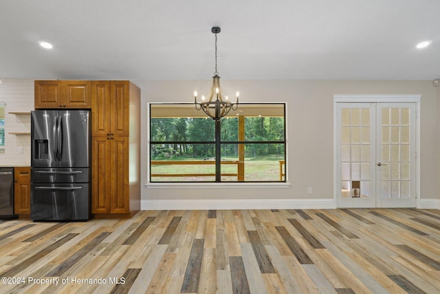 kitchen featuring stainless steel appliances, light hardwood / wood-style floors, an inviting chandelier, and decorative light fixtures