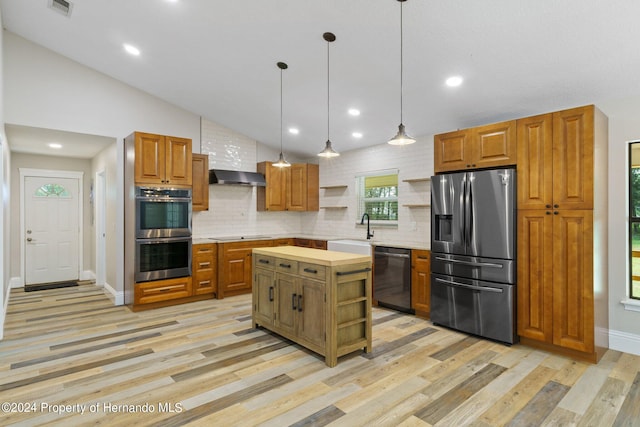 kitchen featuring stainless steel appliances, sink, hanging light fixtures, a center island, and light wood-type flooring