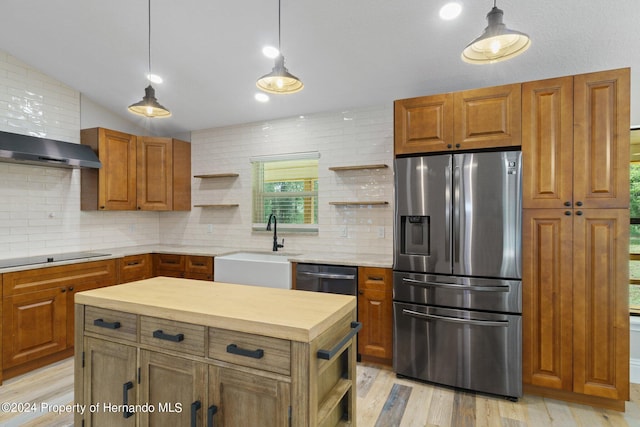 kitchen featuring stainless steel appliances, decorative light fixtures, and light hardwood / wood-style flooring