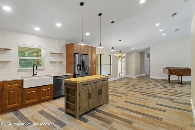 kitchen featuring sink, appliances with stainless steel finishes, light hardwood / wood-style flooring, a kitchen island, and vaulted ceiling