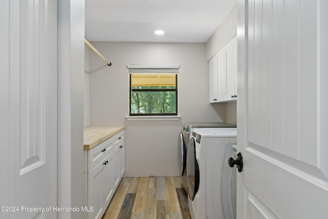 clothes washing area with light hardwood / wood-style flooring, cabinets, and independent washer and dryer