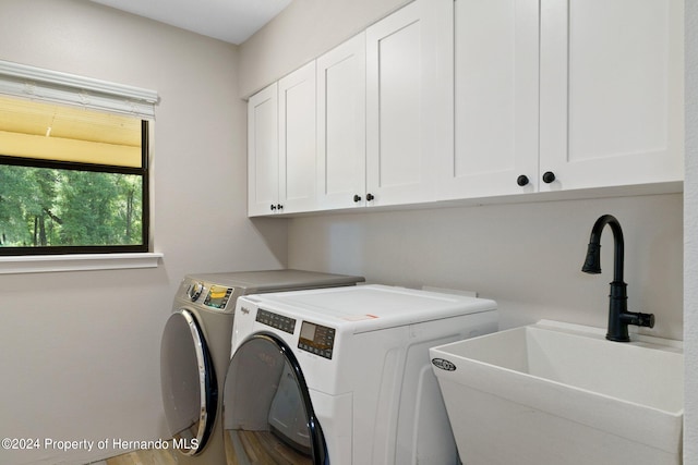 laundry area featuring hardwood / wood-style flooring, washing machine and dryer, cabinets, and sink