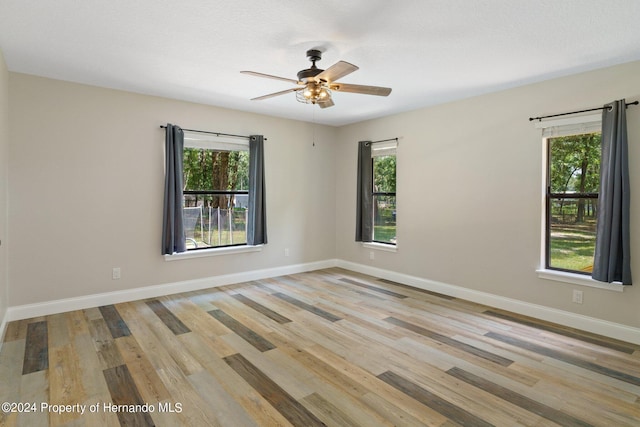 empty room featuring light hardwood / wood-style flooring, ceiling fan, and plenty of natural light