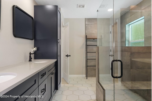 bathroom with walk in shower, vanity, a textured ceiling, and tile patterned floors