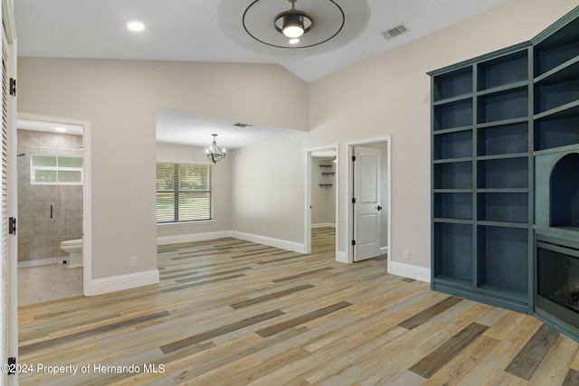 unfurnished living room featuring lofted ceiling, hardwood / wood-style flooring, and ceiling fan with notable chandelier