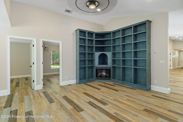 unfurnished living room with hardwood / wood-style floors and vaulted ceiling