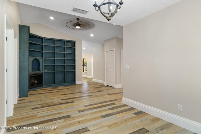 empty room with a textured ceiling, light hardwood / wood-style flooring, and lofted ceiling