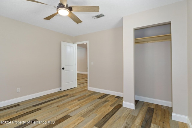 unfurnished bedroom featuring hardwood / wood-style flooring, ceiling fan, and a closet