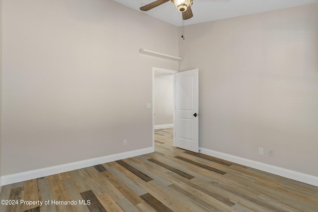 spare room with light hardwood / wood-style floors, ceiling fan, and a high ceiling