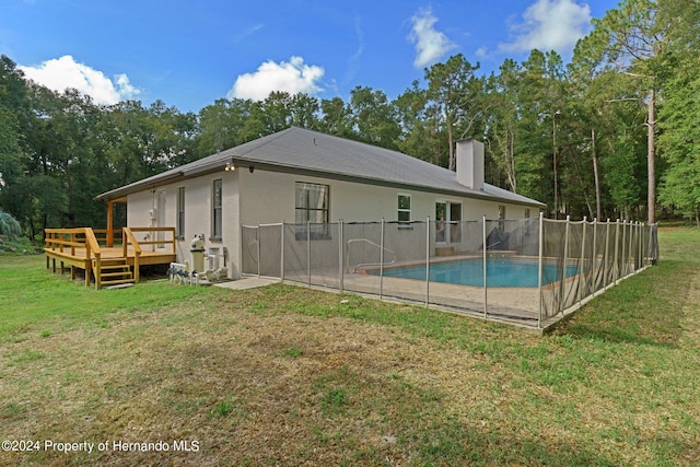 back of house featuring a lawn and a swimming pool side deck