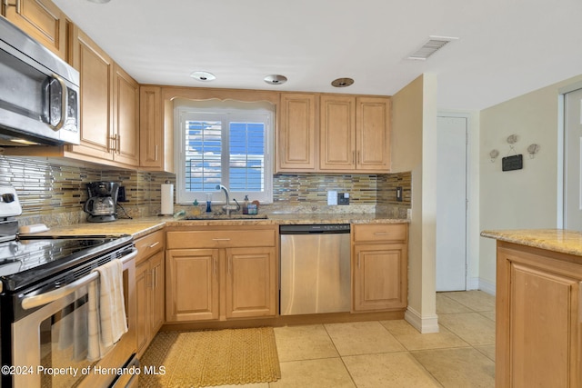 kitchen featuring stainless steel appliances, sink, tasteful backsplash, and light tile patterned floors