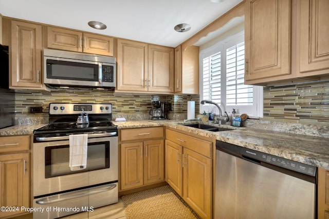 kitchen with stainless steel appliances, light stone counters, and tasteful backsplash