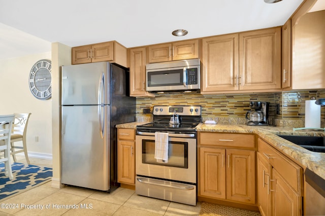 kitchen with light tile patterned flooring, light stone counters, appliances with stainless steel finishes, and tasteful backsplash