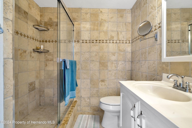 bathroom with walk in shower, vanity, tile walls, and toilet