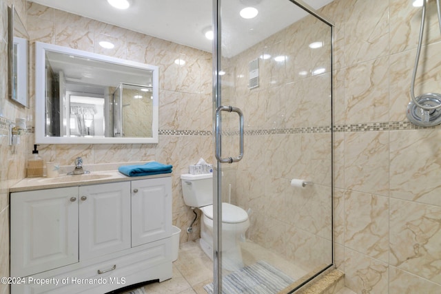 bathroom featuring walk in shower, vanity, tile patterned floors, toilet, and tile walls