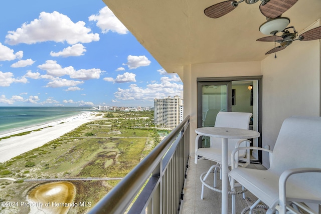 balcony with a water view, a beach view, and ceiling fan