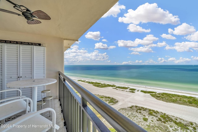 balcony with a water view, a beach view, and ceiling fan