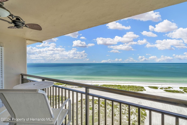 balcony featuring ceiling fan, a view of the beach, and a water view