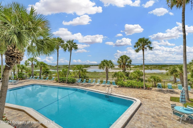 view of swimming pool with a patio and a water view