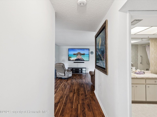 corridor with a textured ceiling and hardwood / wood-style flooring