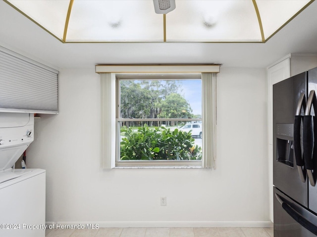 laundry room featuring stacked washing maching and dryer and light tile patterned flooring