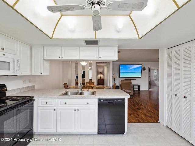 kitchen with black appliances, white cabinetry, sink, light hardwood / wood-style floors, and kitchen peninsula