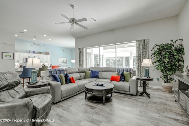 living room with light wood-type flooring, ceiling fan, and lofted ceiling