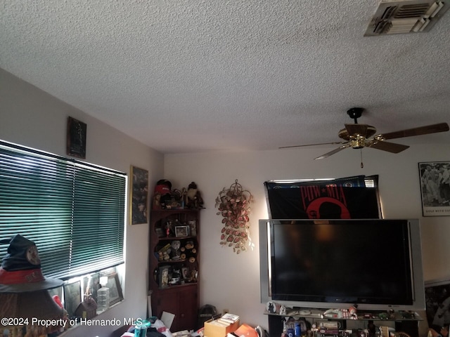 living room with ceiling fan and a textured ceiling