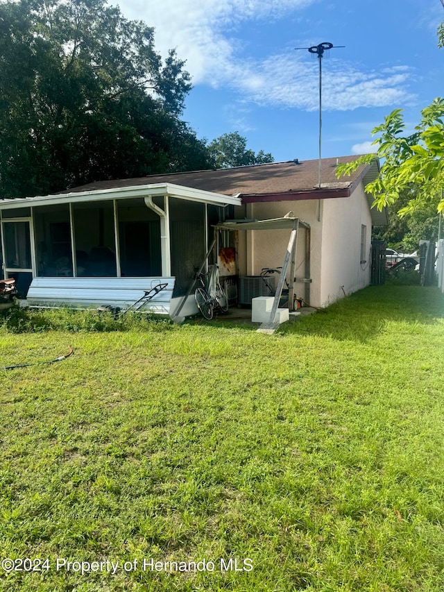 back of house with a sunroom and a lawn