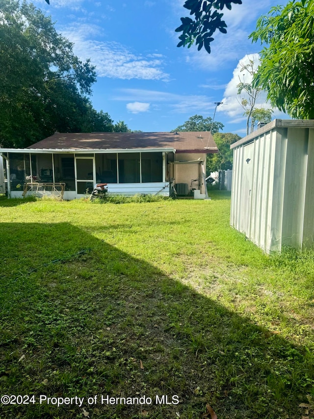 rear view of property with a shed and a lawn