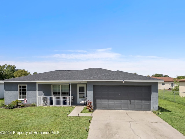 single story home featuring a garage, a porch, and a front yard