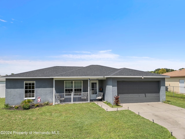 ranch-style house featuring a front yard, a garage, and covered porch