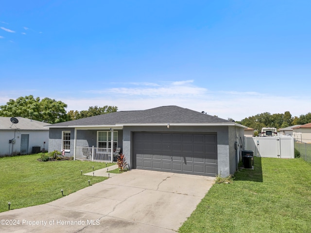 ranch-style house with a garage, a porch, a front lawn, and central AC