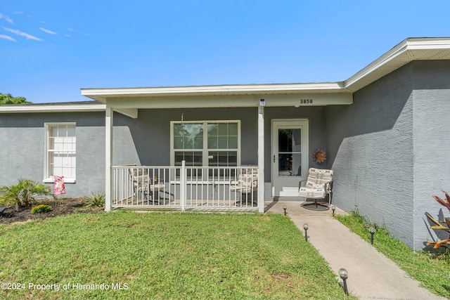 property entrance with covered porch and a lawn