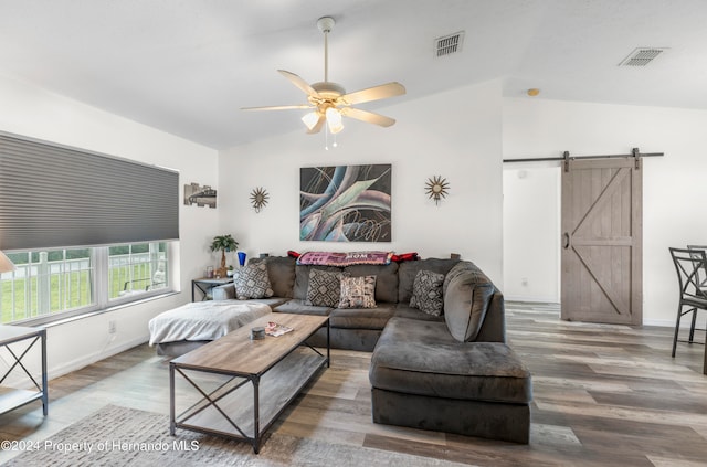 living room featuring wood-type flooring, a barn door, ceiling fan, and vaulted ceiling