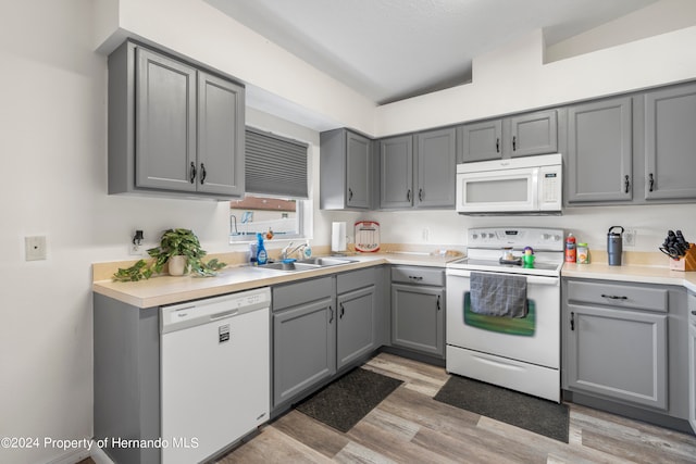 kitchen with gray cabinets, light hardwood / wood-style floors, sink, and white appliances