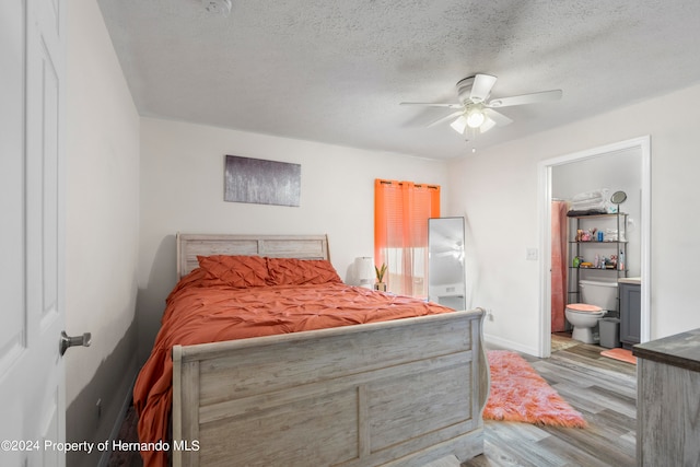 bedroom featuring a textured ceiling, light hardwood / wood-style flooring, ceiling fan, and connected bathroom