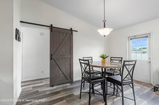 dining room featuring a water view, a barn door, and dark hardwood / wood-style floors