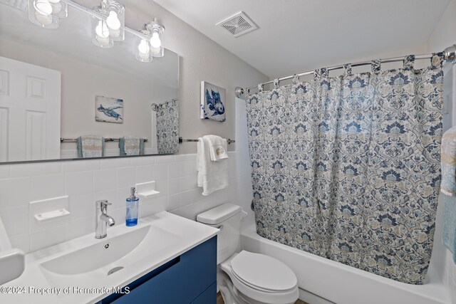 full bathroom featuring shower / bath combo, toilet, tile walls, decorative backsplash, and vanity