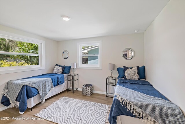 bedroom with multiple windows and hardwood / wood-style flooring