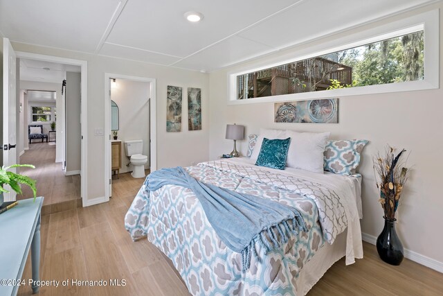 bedroom featuring connected bathroom and light hardwood / wood-style flooring