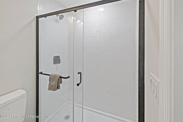 bathroom with toilet and a shower with door