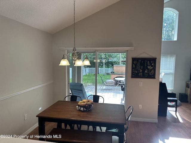 dining space with wood-type flooring, a notable chandelier, and high vaulted ceiling