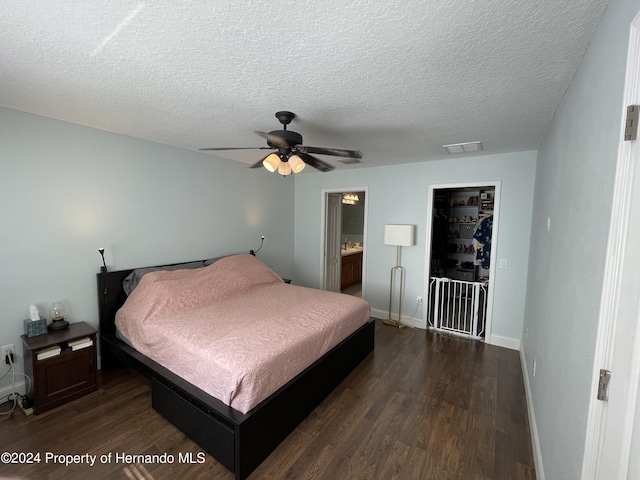 bedroom featuring ceiling fan, dark wood-type flooring, ensuite bathroom, and a textured ceiling