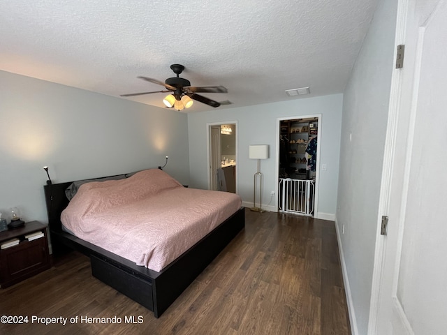 bedroom with ceiling fan, dark wood-type flooring, connected bathroom, and a textured ceiling